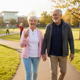 Happy senior couple walking together in park wearing smart rings showing active retirement and healthy aging
