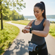 Happy professional woman checking smartwatch health data during coffee break showing wellness lifestyle
